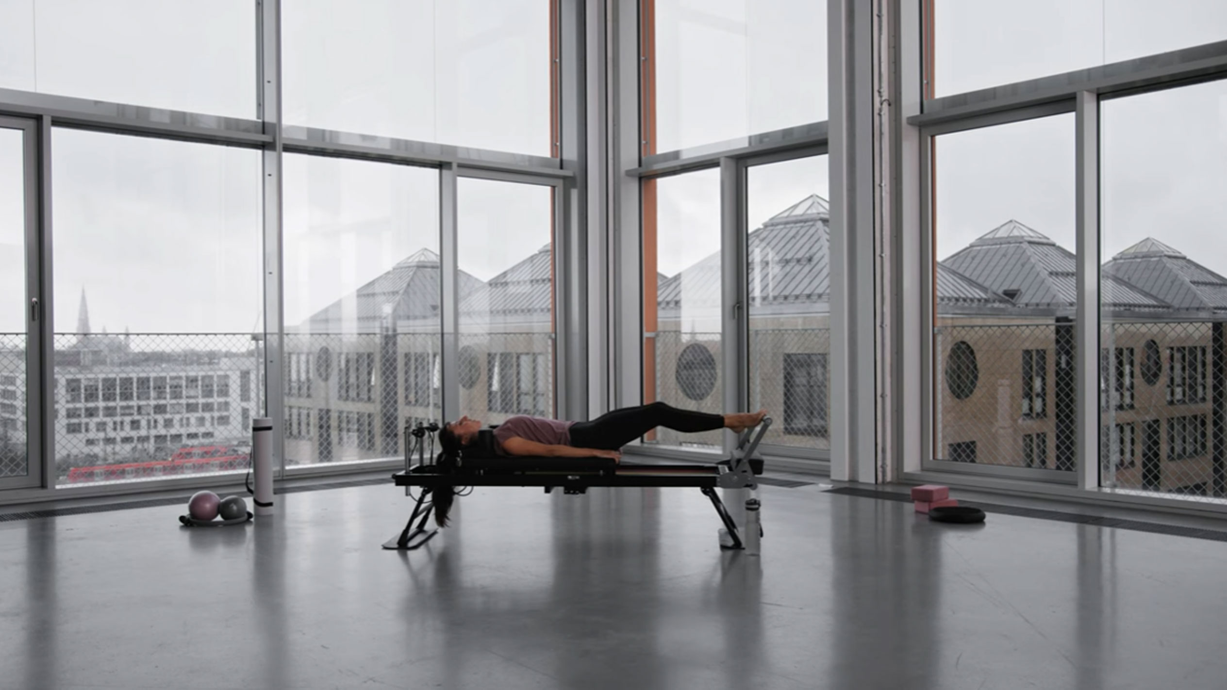 Femme faisant du Pilates dans un studio moderne avec vue sur la ville.