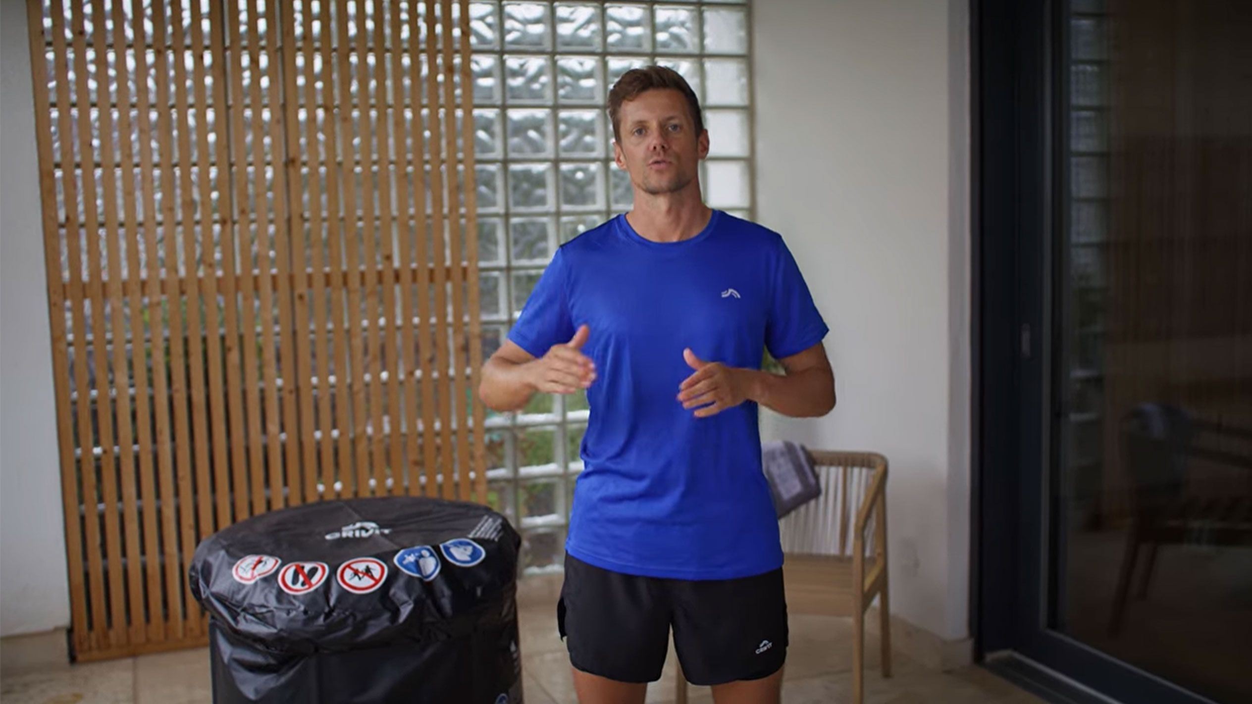 Homme en t-shirt bleu et short noir, à côté d'une couverture de jacuzzi noire.