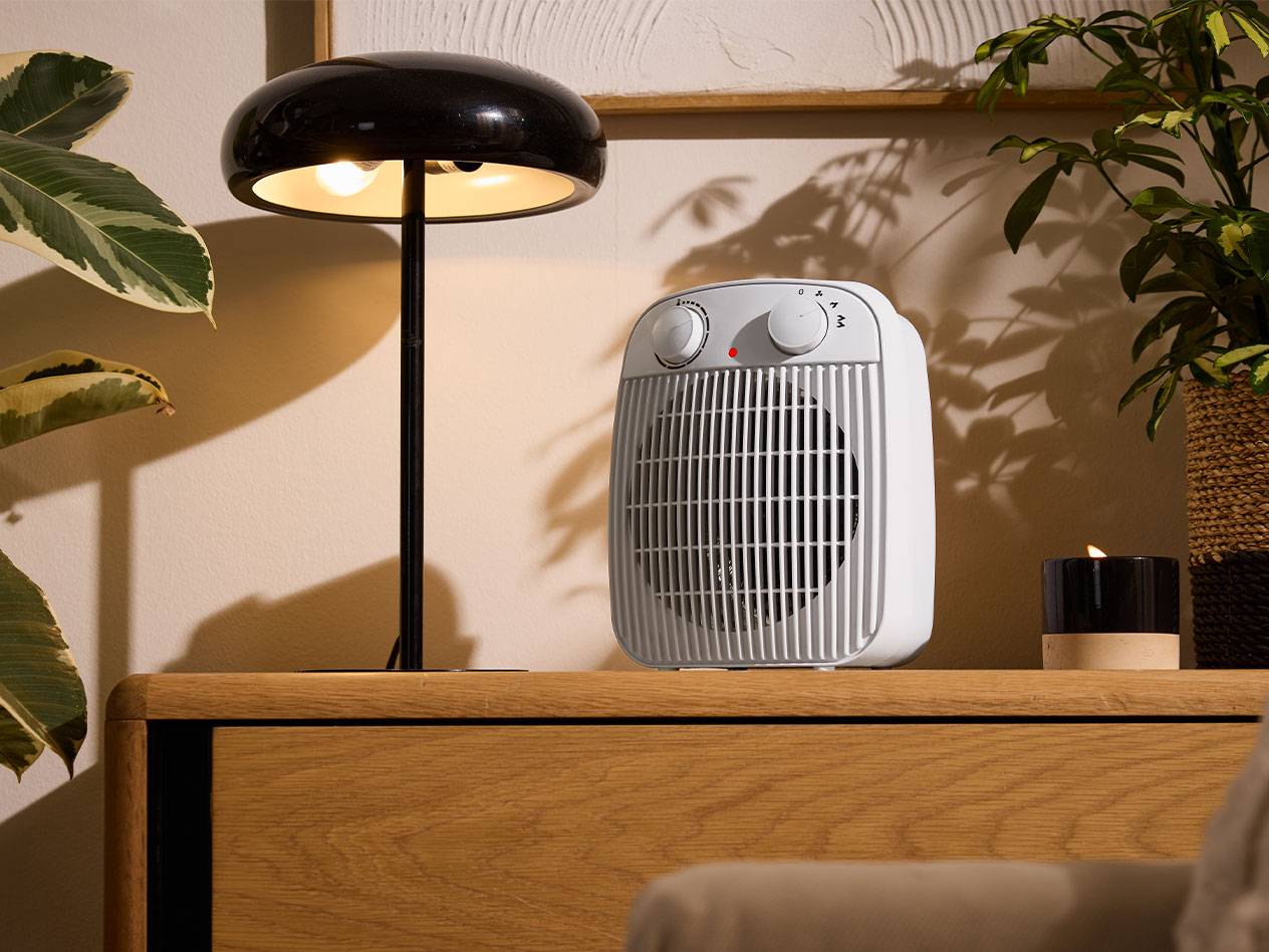 Chauffage blanc et lampe de table noire sur un meuble en bois dans une pièce chaleureuse.