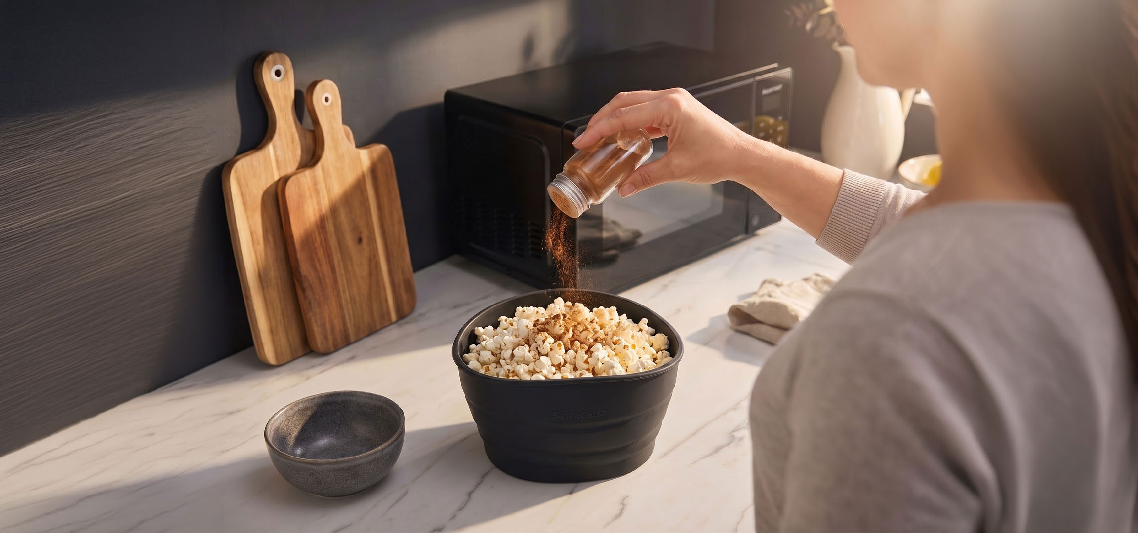Généré par IA: Popcorn dans un bol noir assaisonné d'épices, à côté de planches à découper en bois.