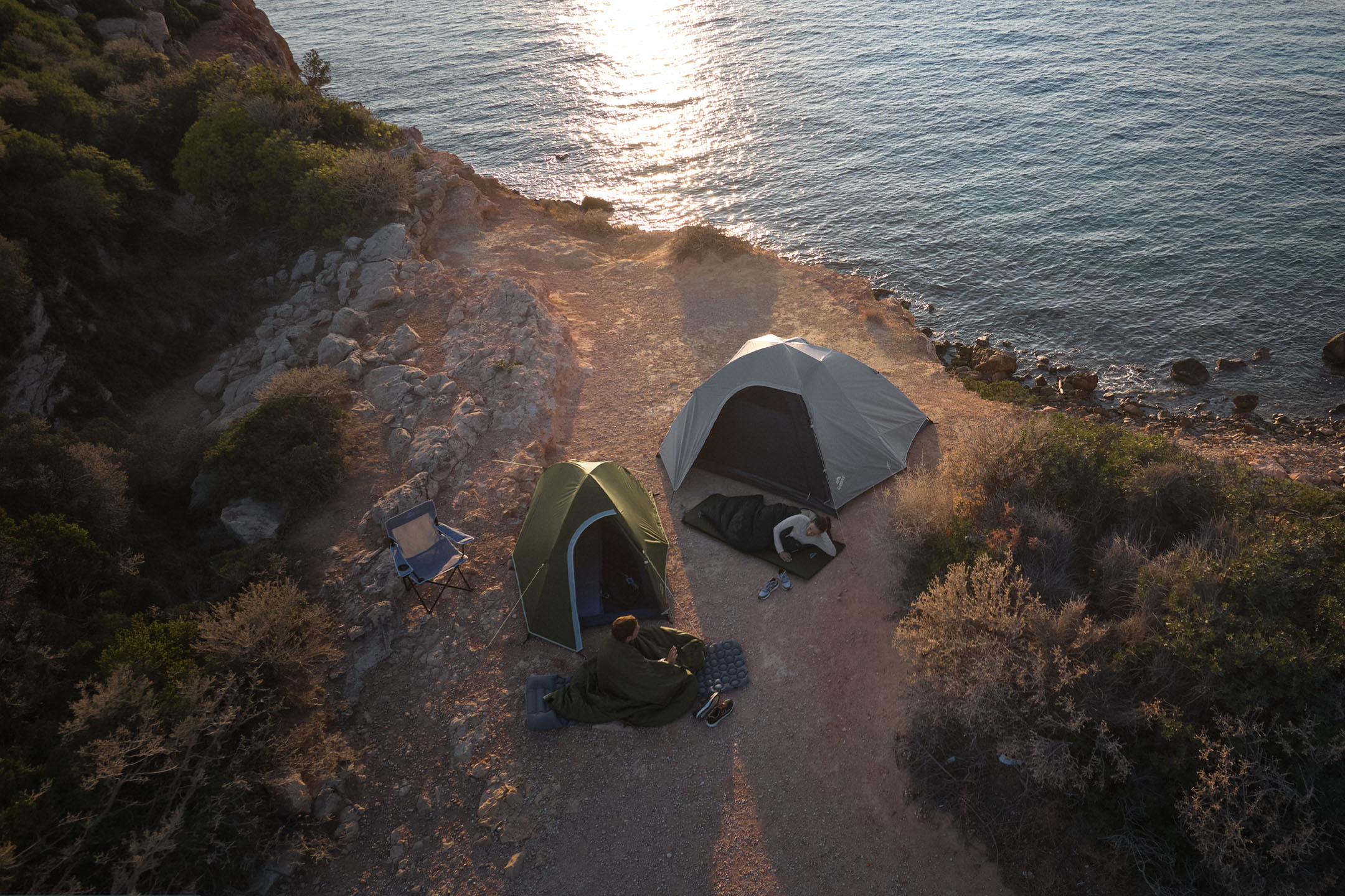Deux tentes et sacs de couchage sur la côte au coucher du soleil.