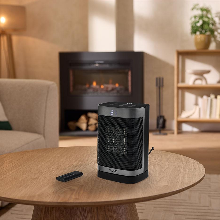 Chauffage céramique portable avec télécommande sur une table en bois.