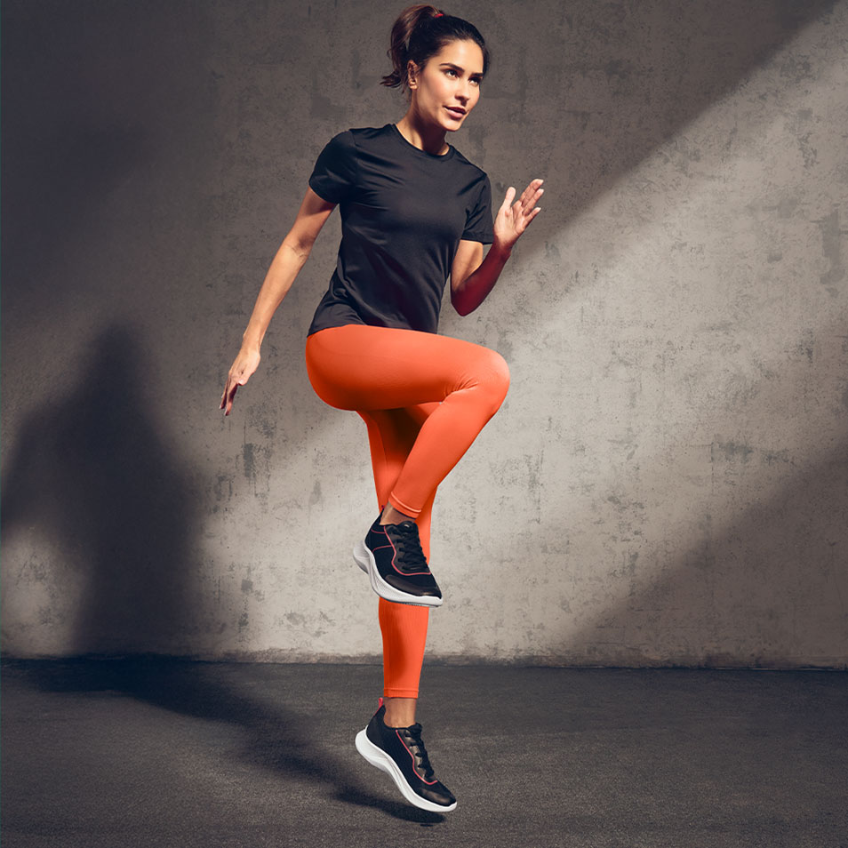 Femme en t-shirt de sport noir et leggings orange faisant de l'exercice