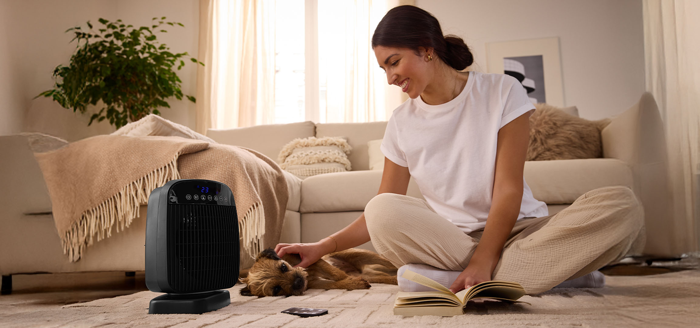 Une femme joue avec un chien à côté d'un radiateur électrique dans un salon.