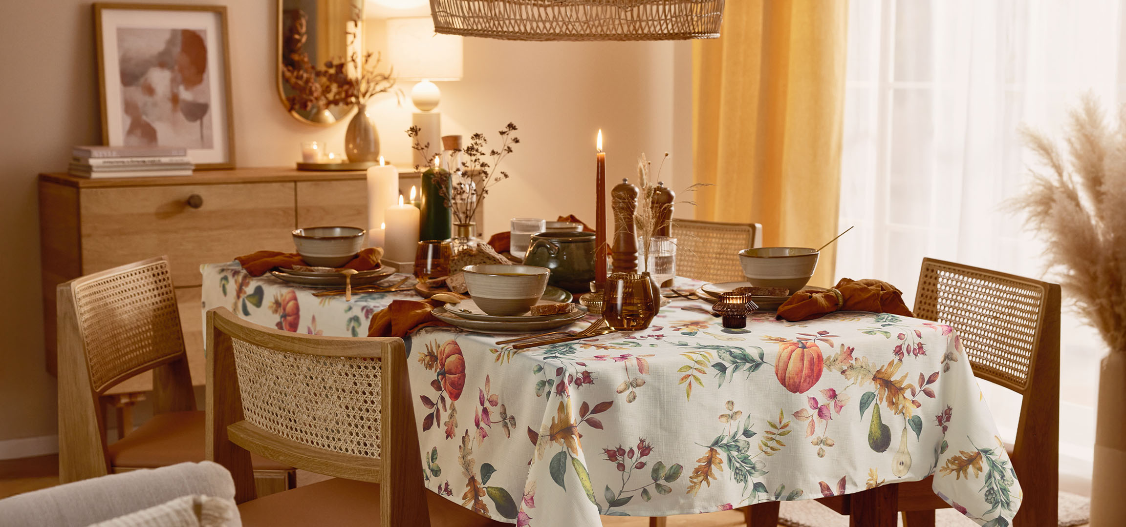 Salle à manger avec une table dressée, nappe florale et éclairage chaleureux.