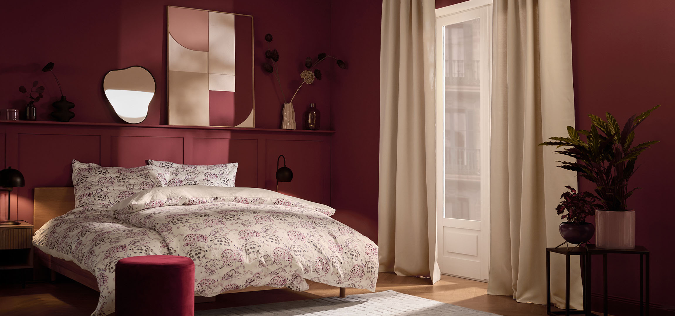 Chambre avec murs marrons, lit avec literie blanche à motifs floraux et plantes.