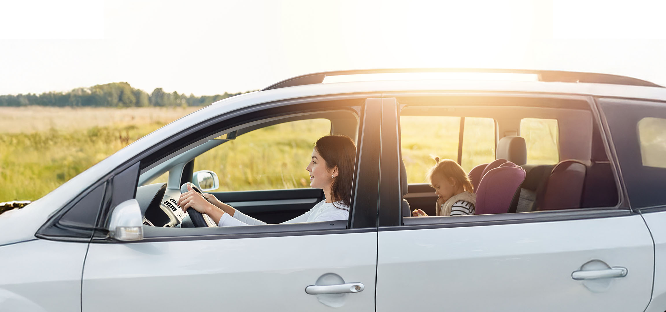 Une femme conduit une voiture avec sa fille sur le siège arrière.