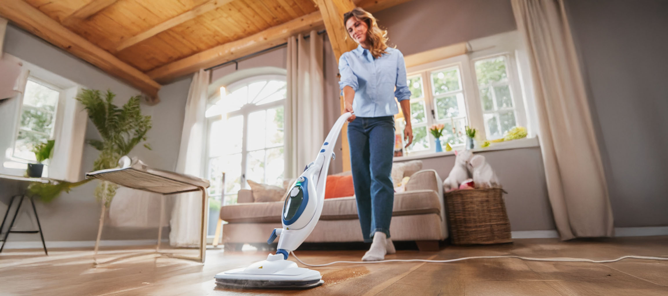 Femme nettoyant un plancher en bois avec une serpillière à vapeur.