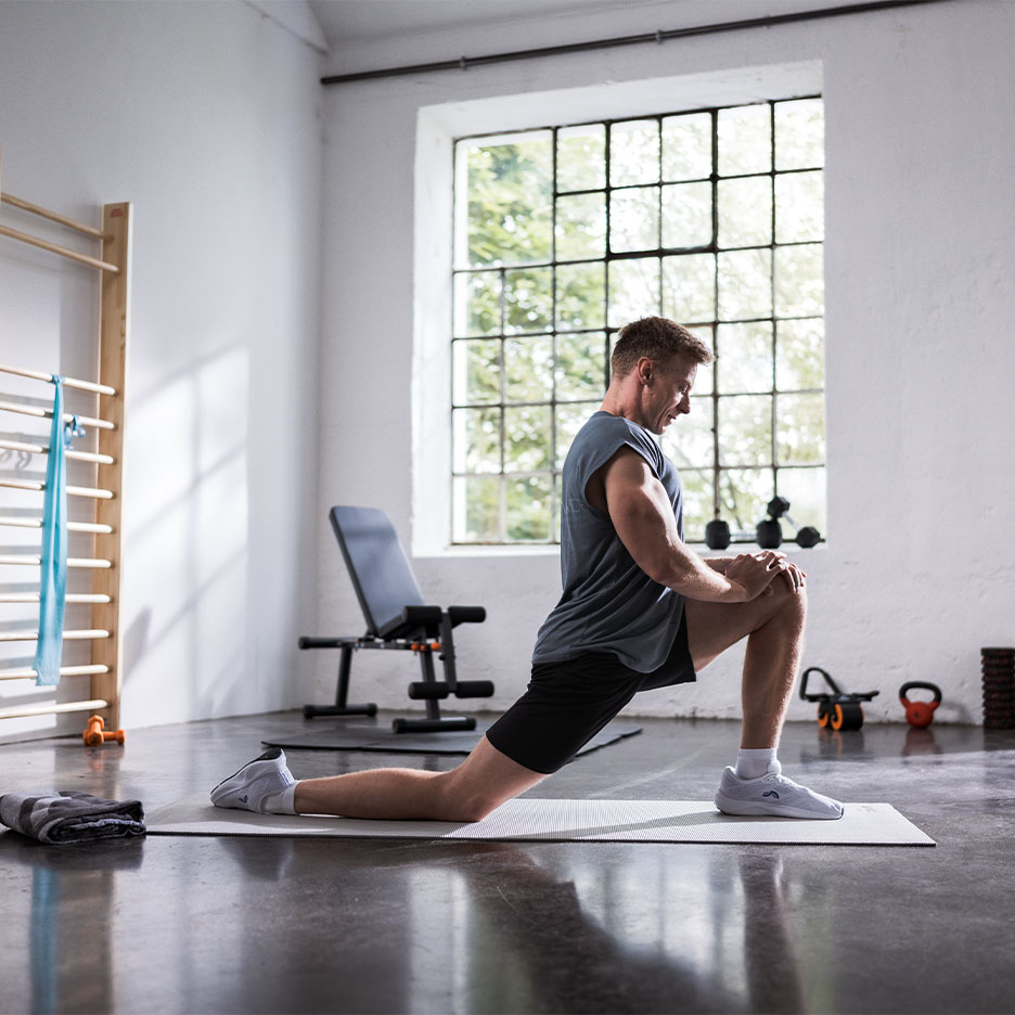 Homme s'étirant sur un tapis de yoga dans une salle de sport.